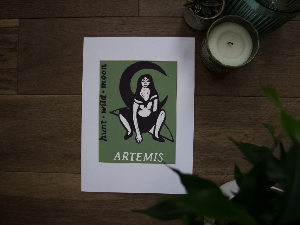 Artistic representation of the Greek Goddess Artemis, sitting on a green background with the words 'hunt wild moon' and her name 'ARTEMIS' displayed prominently.