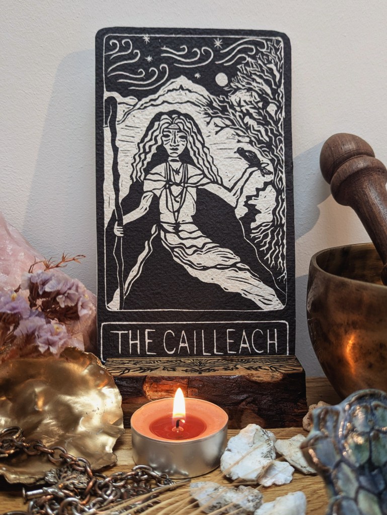 The cailleach oracle card in wooden oracle stand with candle in front lke an altar